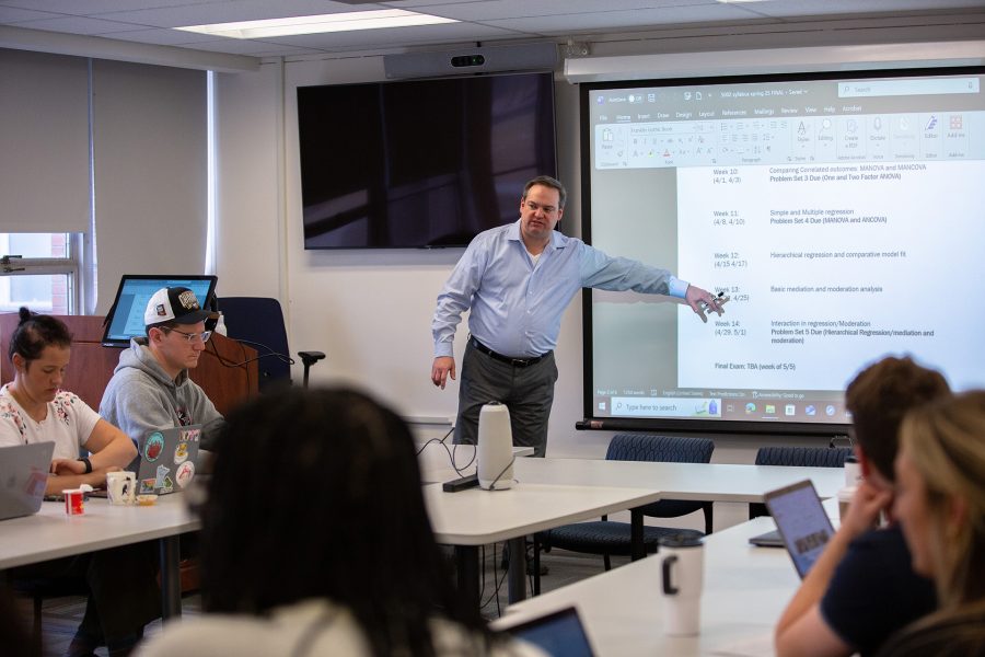 A professor points to the projector screen during a communication class.